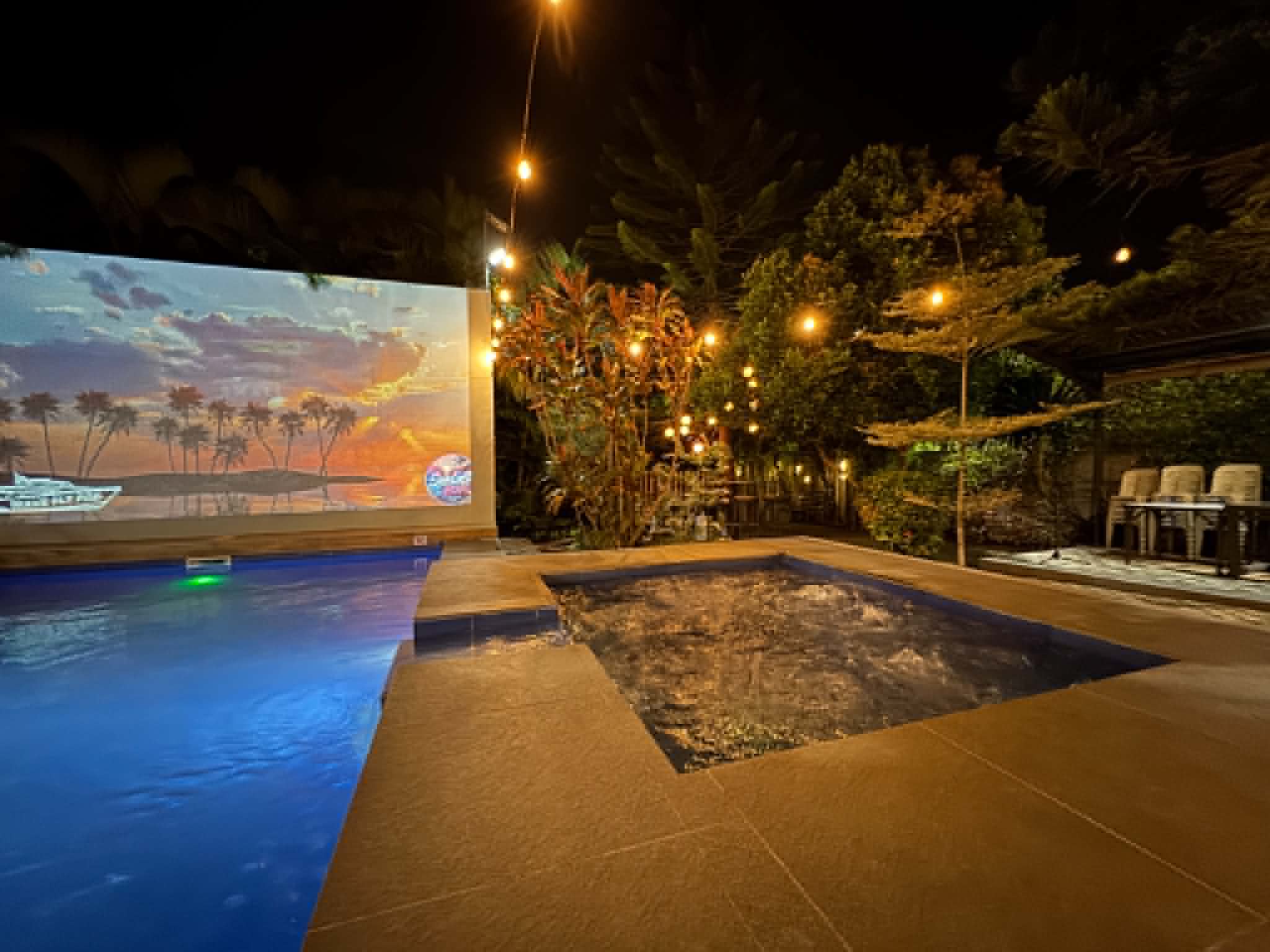 Villa 1 pool and jacuzzi at night with projector screen and garden lights