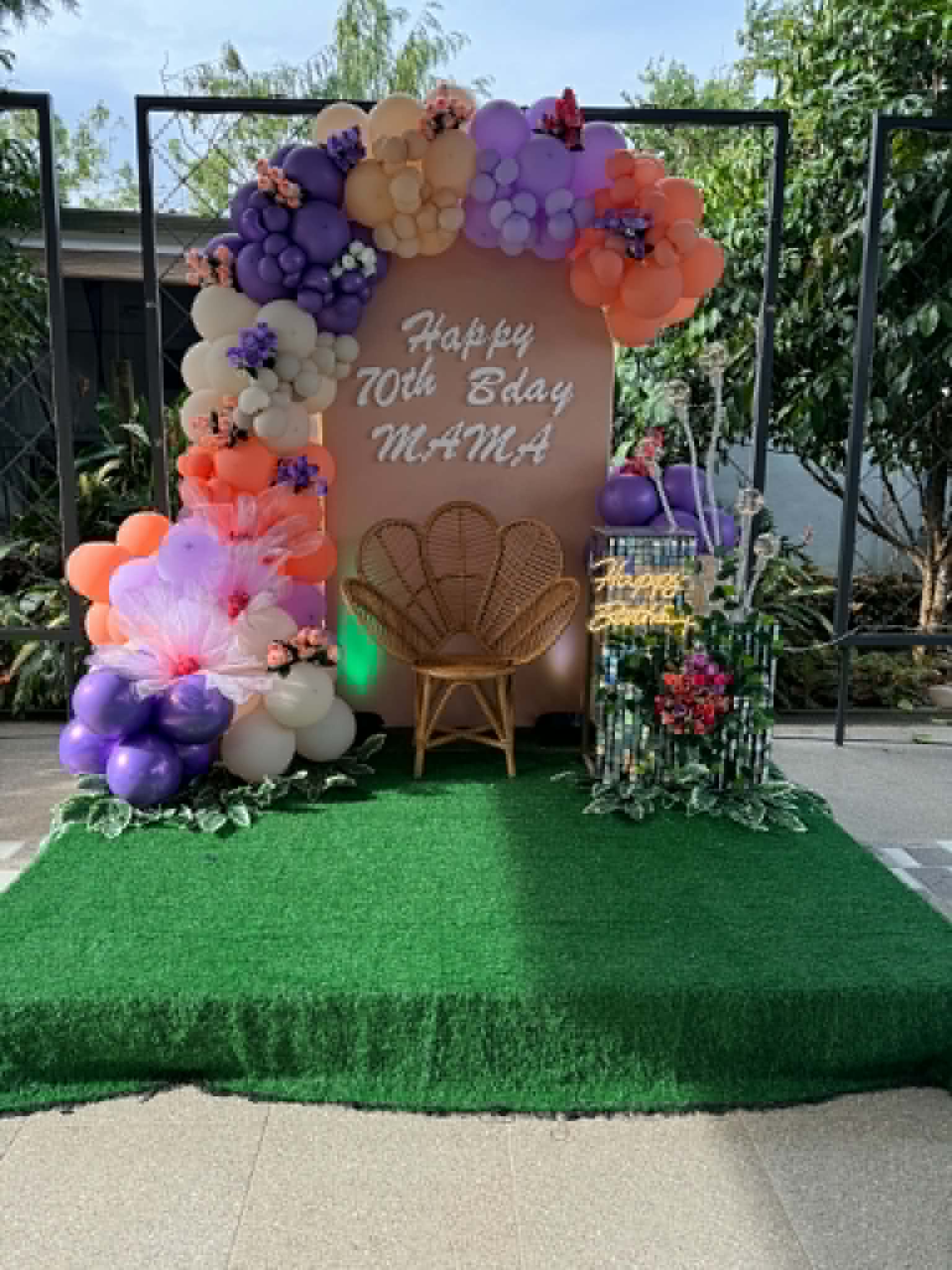 Villa 1 70th birthday backdrop with colorful balloons and a rattan chair