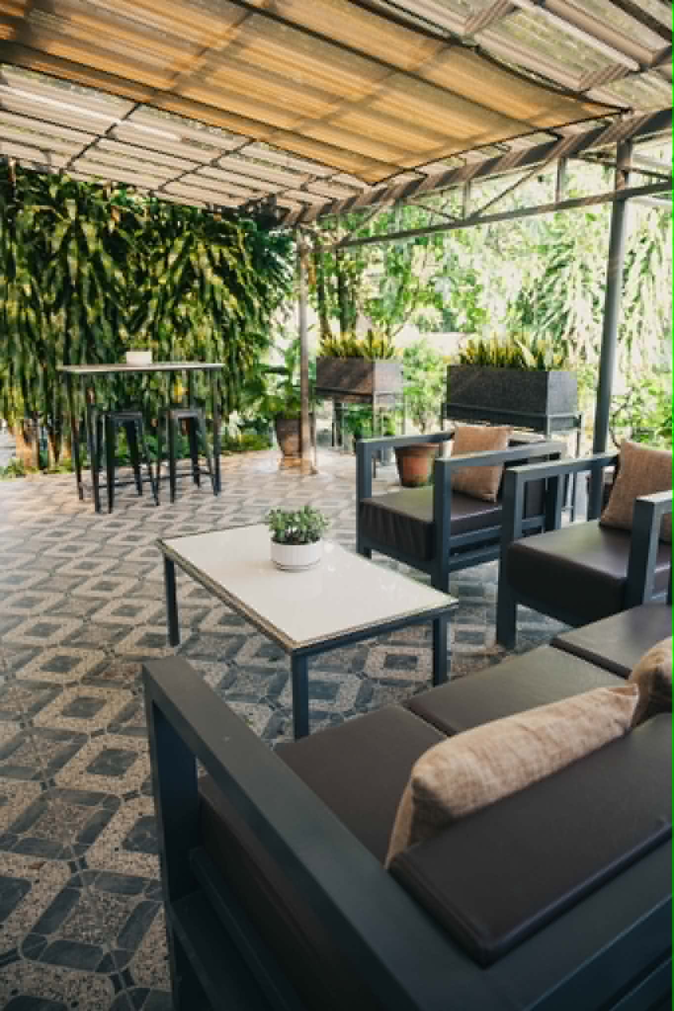 Villa 1 open-air lounge with covered seating and greenery