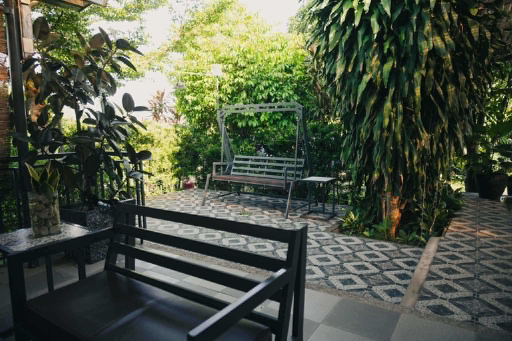 Villa 1 garden lounge area with swing bench and tropical plants