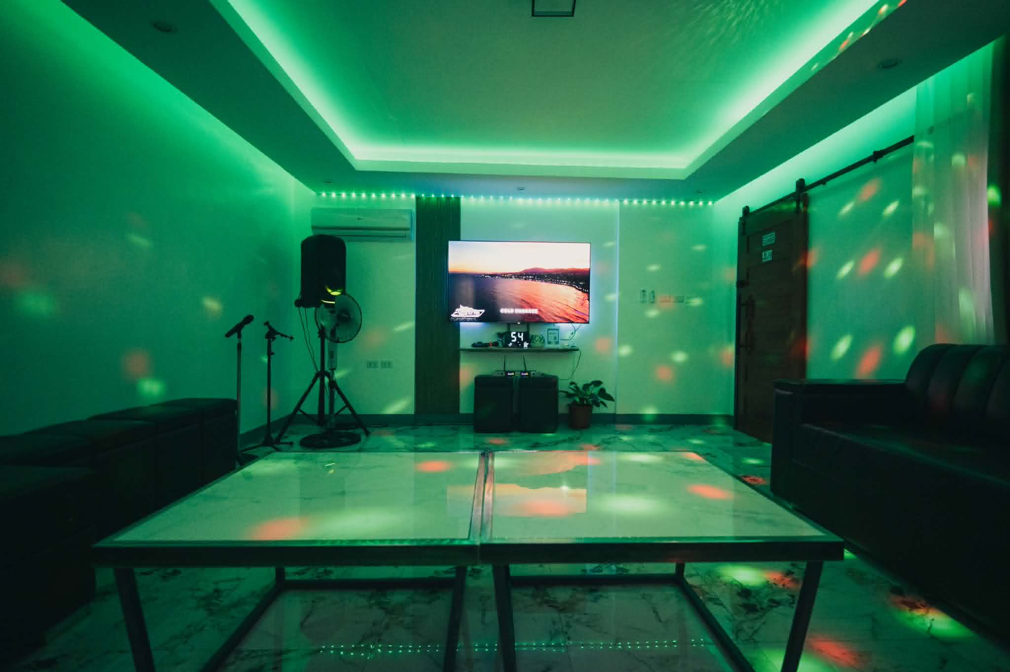 Villa 2 entertainment room with TV, microphones, speaker, and party lights